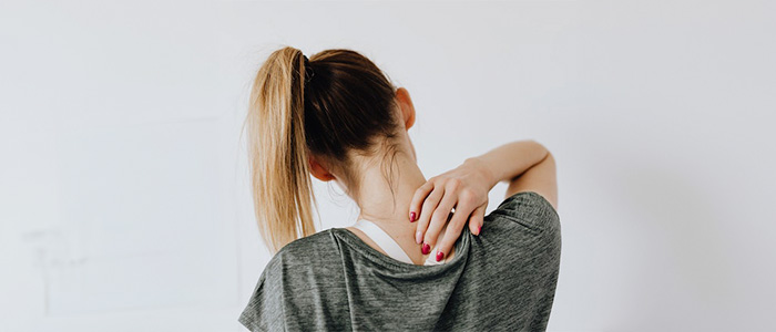 A woman touching the back of her neck
